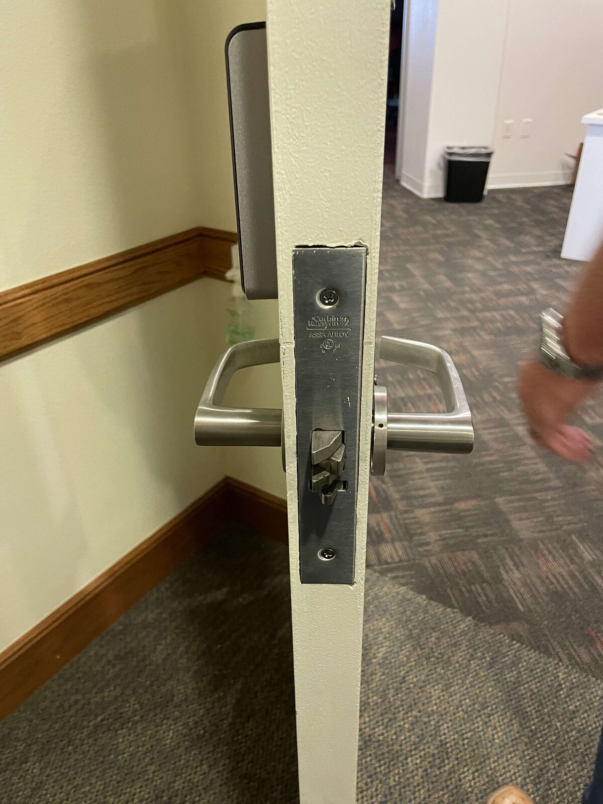 Commercial mortise lock hardware installed in a door edge, close-up detail