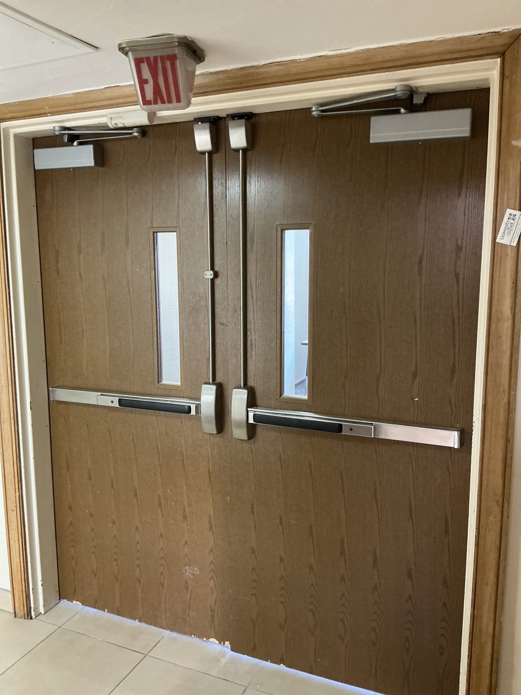 Panic exit hardware installed on commercial wood-faced double doors