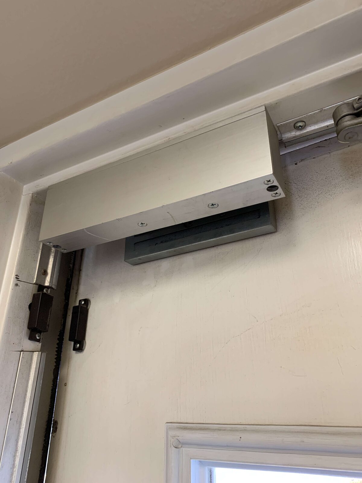 Surface-mounted automatic door operator installed above a commercial entry door